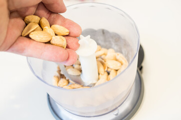 Person pouring almonds into the grinder to grind them