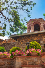 Monastery courtyard with potted flowers and bell tower in Meteora Greece