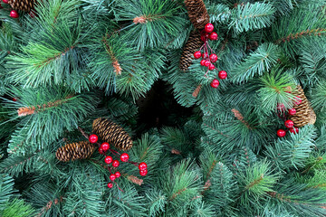 A festive evergreen Christmas wreath is decorated with red berries and pinecones for a traditional holiday