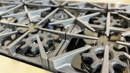 a close-up view of multiple industrial gas stove burners with cast iron grates