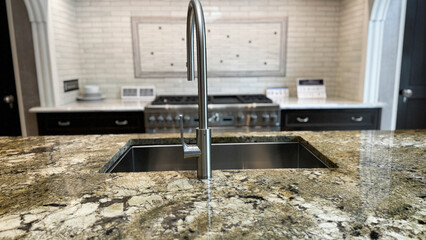 a modern kitchen island with a granite countertop and a sleek stainless steel faucet, with a stove and tiled backsplash