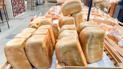 freshly baked loaves of bread arranged in neat rows on wooden trays inside a bakery or supermarket