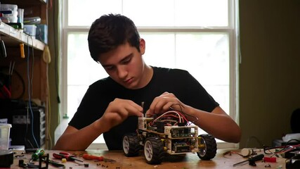 Teenager assembles a robot car with concentration, showcasing robotics and engineering skills at - Powered by Adobe