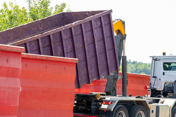 Truck is loading a garbage container for recycling material. Container is inclined in the air.