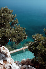 Luxury coastal swimming pool with turquoise water and Mediterranean sea view from above

