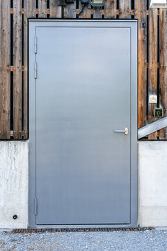 Metal door with contemporary lock, motion detector and light above. Badge reader on the right. Concrete and wooden panel wall.