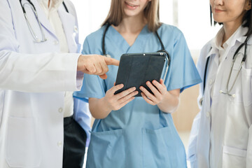 Unknown Caucasian woman doctor use tablet computer with team working at hospital 