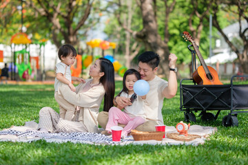 Young family having a fun picnic in the park, blowing bubbles and enjoying the outdoors.
