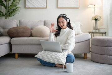 Cheerful female wearing headphones having an online meeting from home.