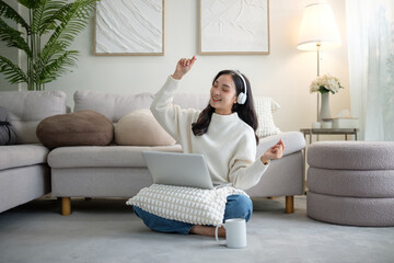 Obraz premium Happy young Asian woman enjoying music while working from home.