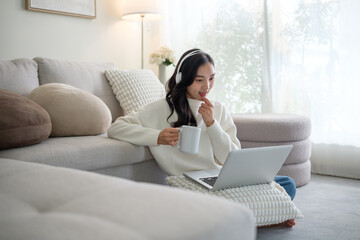 Young woman sitting comfortably on the floor with a laptop, working or studying from home in a bright living room.