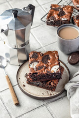 Homemade chocolate brownie cake with cookies with coffee on a plate on gray tile background