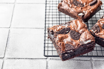 Homemade chocolate brownie cake with cookies on baking rack close up on gray tile background