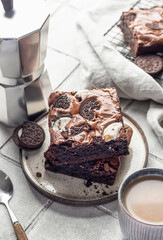 Homemade chocolate brownie cake with cookies with coffee on a plate on gray tile background