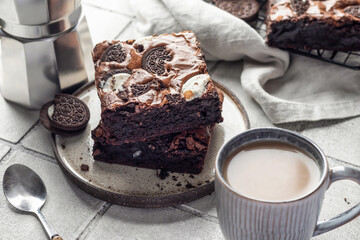 Homemade chocolate brownie cake with cookies with coffee on a plate on gray tile background