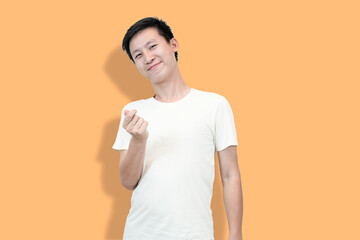 A young Asian man smiles and makes a mini heart gesture with his fingers