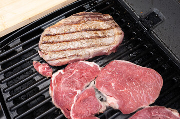 Grilling fresh steak cuts on outdoor barbecue with charred grill marks