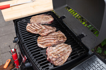 Juicy steaks grilling on outdoor bbq with searing marks on black grill