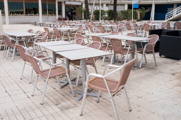 Empty outdoor cafe with pink chairs and tables on a patio