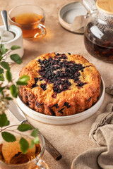 Blueberry cake on a plate on beige background with tea