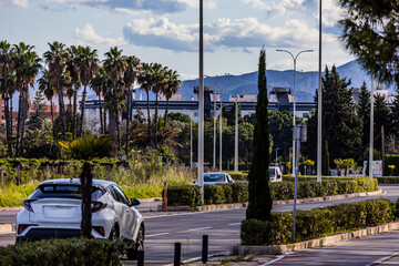 Cars drive along a road with greenery and palm trees in the background in the city of Gandia, Spain	

