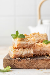 Lemon crumble bars on wooden cutting board on white tile background with text space. Oatmeal lemon bars