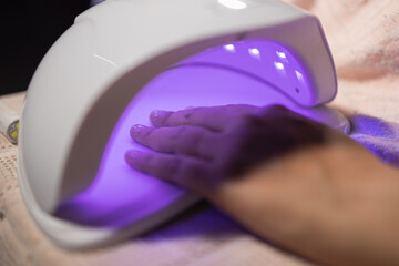 Hand placed under UV light in home nail salon for beauty treatment enhancing fashion and art with...