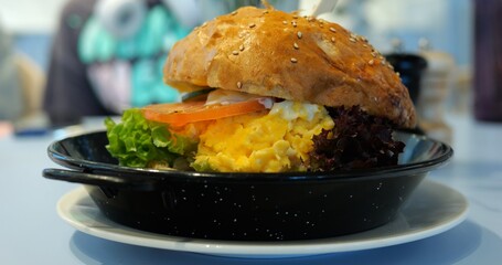 Artisanal burger with layers of creamy scrambled eggs lettuce and tomato. Symphony of flavors...