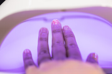 Nail art and beauty treatment at home nail salon with hand under UV light for fashion style and care