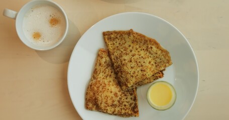 WARSAW, POLAND - MARCH 10 2023: Cafe table serves hearty delicious breakfast with hot and sweet dishes. Fried eggs make up main meal while pancakes with cup of coffee serve as dessert