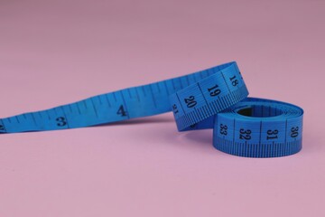 Blue measuring tape isolated on pink background. diet for weight loss concept.