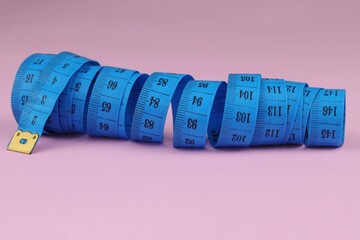 Blue measuring tape isolated on pink background. diet for weight loss concept.