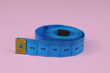 Blue measuring tape isolated on pink background. diet for weight loss concept.