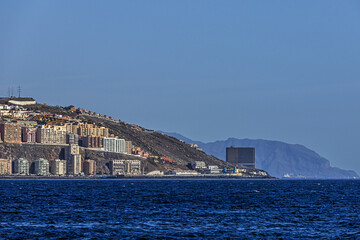 Mountains and buildings on the horizon on the shore of the blue Atlantic Ocean on the island of Tenerife under a clear sky	
