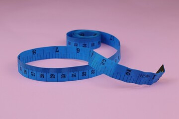Blue measuring tape isolated on pink background. diet for weight loss concept.