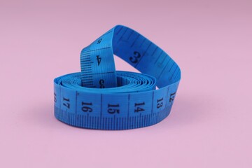 Blue measuring tape isolated on pink background. diet for weight loss concept.