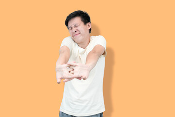 A young Asian man in a white t-shirt stretches his arms
