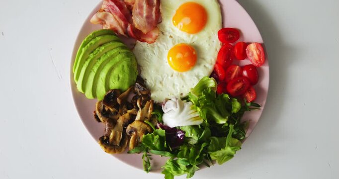 Fresh and healthy ingredients for special keto breakfast lie on thin plate. Scrambled eggs with vegetables and bacon allow person to adhere to low-carb diet