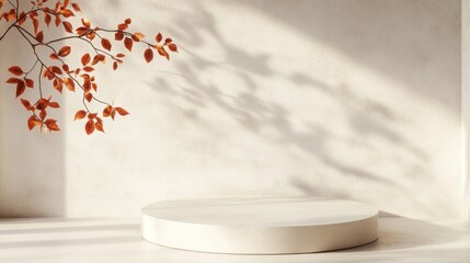 Empty round beige concrete podium in minimalist setting with red autumn leaves and shadows on wall. Perfect for displaying seasonal fall products