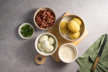 Cooking egg potato salad with bacon and fresh herbs in a plate