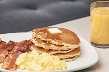 American Diner Breakfast with pancakes, scrambled eggs, crispy bacon, hash browns, orange juice