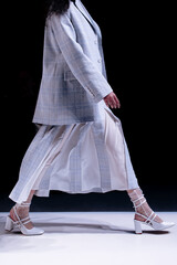 Woman wearing tweed jacket and white skirt, classic fashion clothing on black background