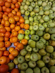 A vibrant display of fresh oranges and green apples arranged in neat rows. The oranges are bright and round, while the apples are smooth and shiny.