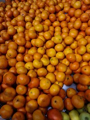 A large pile of fresh, ripe oranges and tangerines in various shades of orange and yellow. The fruits are arranged closely together, showcasing their vibrant colors.