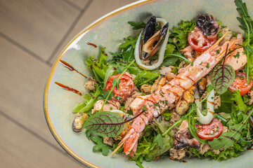 A vibrant seafood salad featuring grilled shrimp, mussels, squid, cherry tomatoes, fresh greens,...