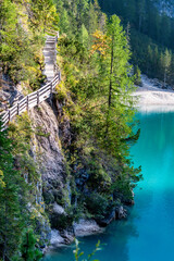 Scenic trail beside the stunning Lago di Braies in South Tyrol. Bright blue-green waters contrast...