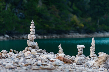 Artful stone cairns standing tall by tranquil waters. Representing stability, balance, and human...
