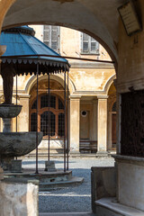 Archway View of Historical Courtyard with Fountain and Vintage Architecture