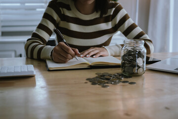 A woman holds a piggy bank, which symbolizes savings, financial planning, and economic challenges....