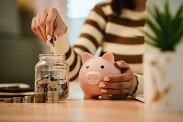 A woman holds a piggy bank, which symbolizes savings, financial planning, and economic challenges....